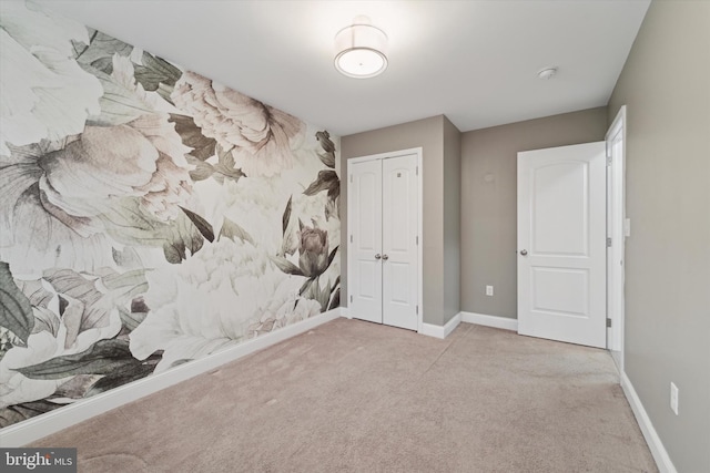 unfurnished bedroom featuring light carpet and a closet