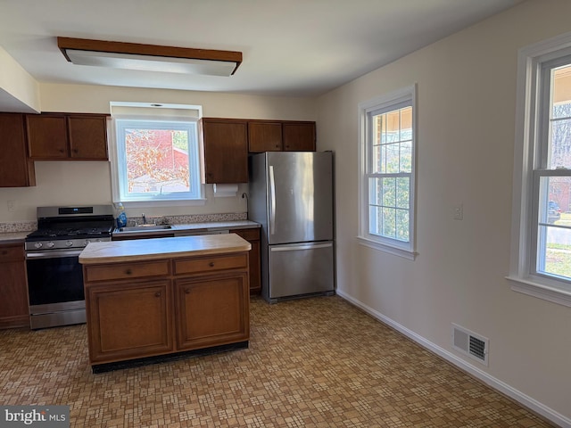 kitchen with appliances with stainless steel finishes, light countertops, visible vents, and a sink