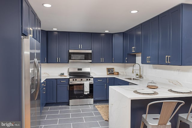 kitchen with sink, blue cabinetry, light stone countertops, and appliances with stainless steel finishes