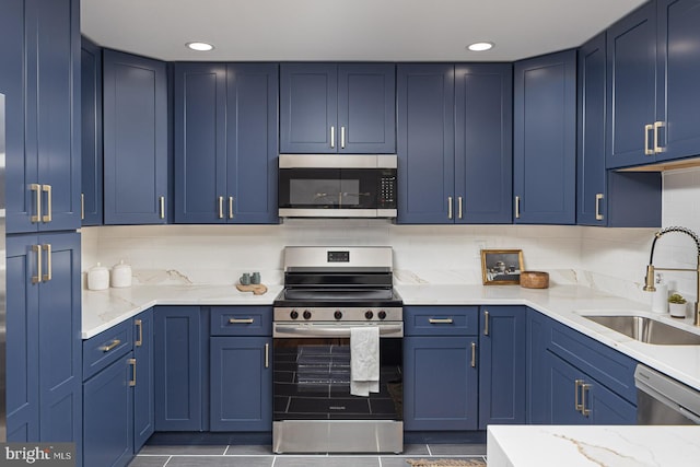 kitchen featuring sink, appliances with stainless steel finishes, light stone countertops, blue cabinets, and decorative backsplash