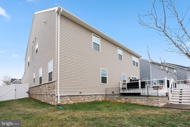 back of property with a wooden deck and a lawn