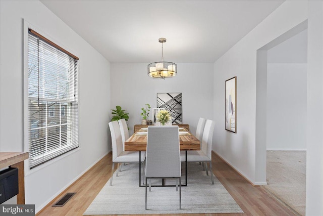 dining space with a notable chandelier and light hardwood / wood-style flooring