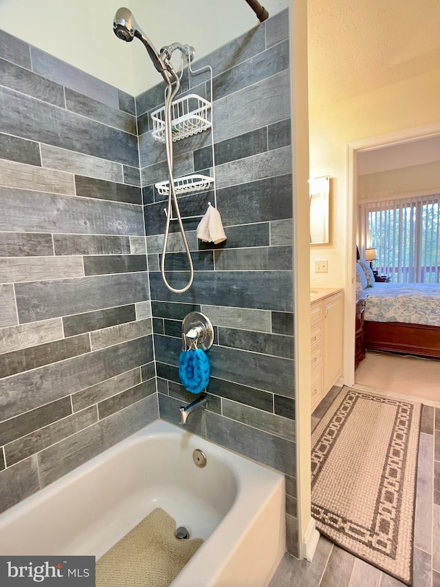 bathroom with tiled shower / bath combo and vanity