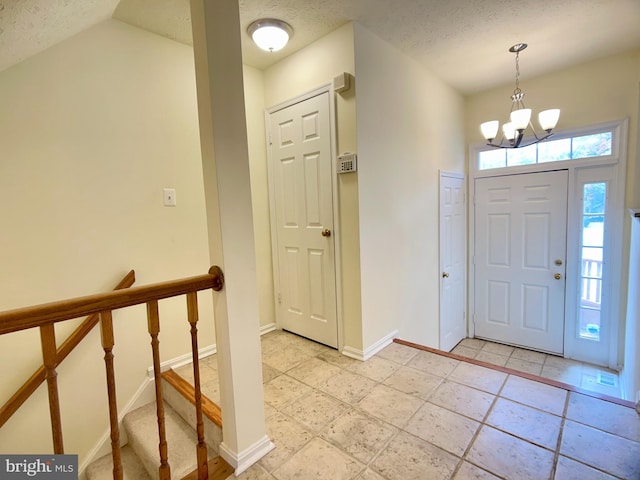 entryway featuring a textured ceiling, a notable chandelier, and vaulted ceiling