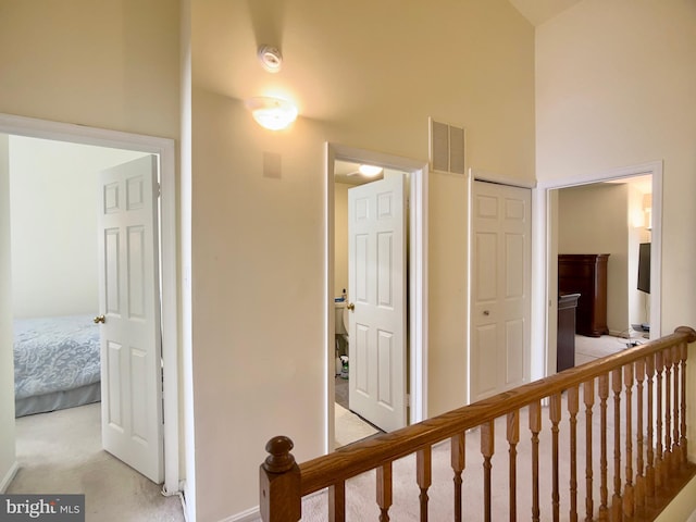 hall with a high ceiling and light carpet