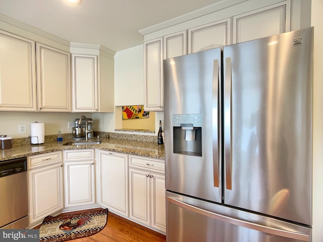 kitchen with sink, light stone counters, light hardwood / wood-style flooring, and stainless steel appliances