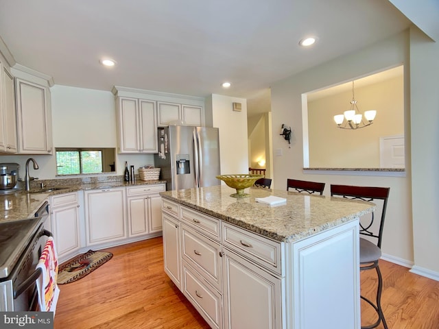 kitchen with a center island, stainless steel refrigerator with ice dispenser, sink, decorative light fixtures, and white cabinets