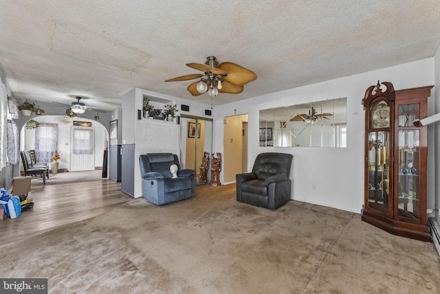 sitting room with arched walkways, ceiling fan, and a textured ceiling