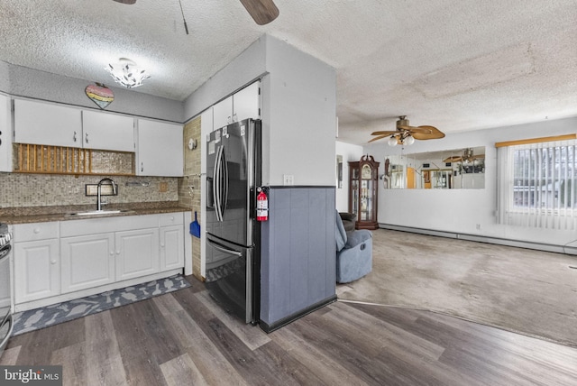 kitchen with a baseboard heating unit, stainless steel refrigerator with ice dispenser, a sink, and white cabinetry