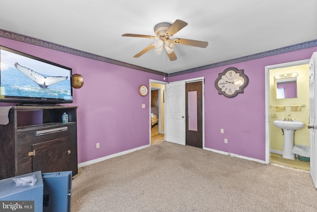 carpeted bedroom featuring a ceiling fan, a sink, connected bathroom, and baseboards