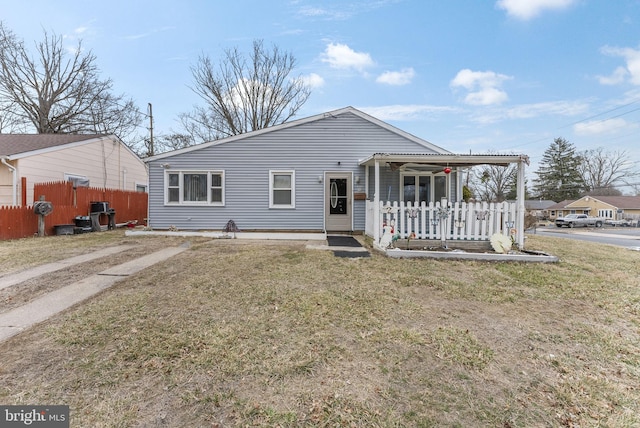 view of front of property with covered porch, fence, and a front lawn