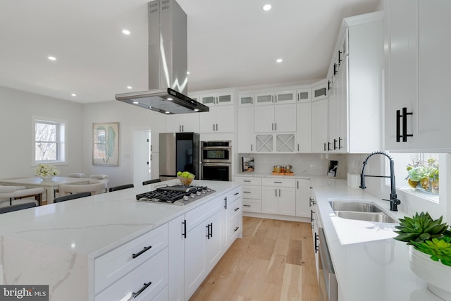 kitchen featuring a kitchen island, island range hood, white cabinetry, and stainless steel appliances