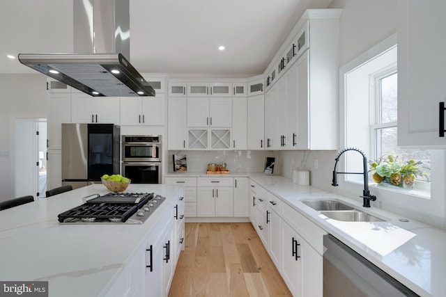 kitchen featuring sink, white cabinets, light stone countertops, island range hood, and stainless steel appliances