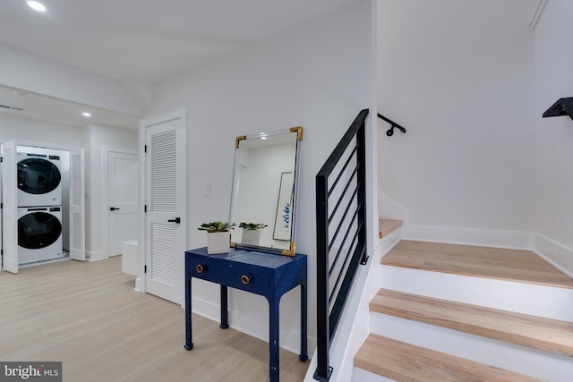 stairway featuring wood-type flooring and stacked washer / dryer