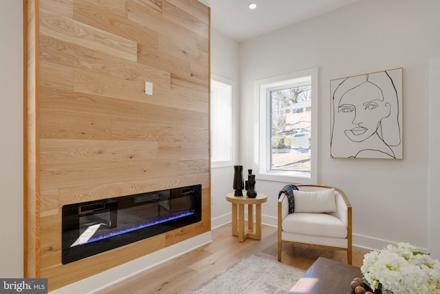 sitting room featuring a tile fireplace and light hardwood / wood-style flooring