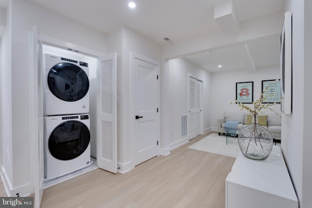 clothes washing area with light hardwood / wood-style floors and stacked washer / dryer