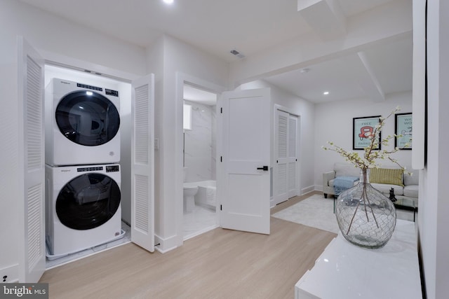 laundry room featuring light hardwood / wood-style floors and stacked washer / dryer