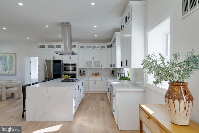 kitchen featuring sink, white cabinets, island range hood, and a center island