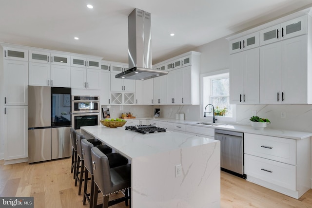 kitchen with a kitchen island, island range hood, white cabinetry, and appliances with stainless steel finishes