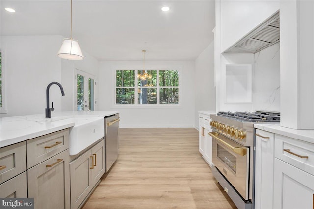 kitchen featuring light stone countertops, hanging light fixtures, sink, and stainless steel appliances