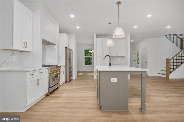 kitchen featuring a center island with sink, pendant lighting, high quality appliances, and white cabinets