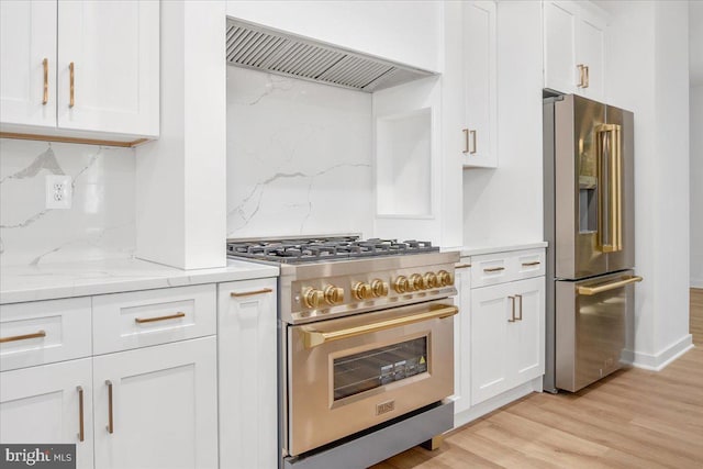 kitchen with decorative backsplash, high quality appliances, white cabinetry, and custom range hood