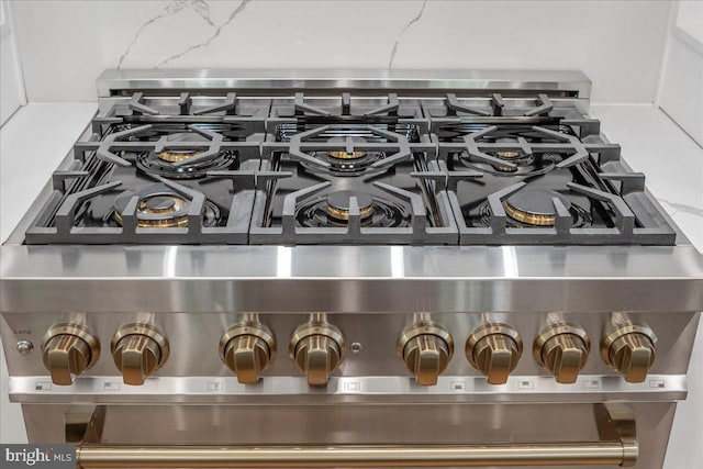 interior details featuring light stone countertops, backsplash, and high end stove