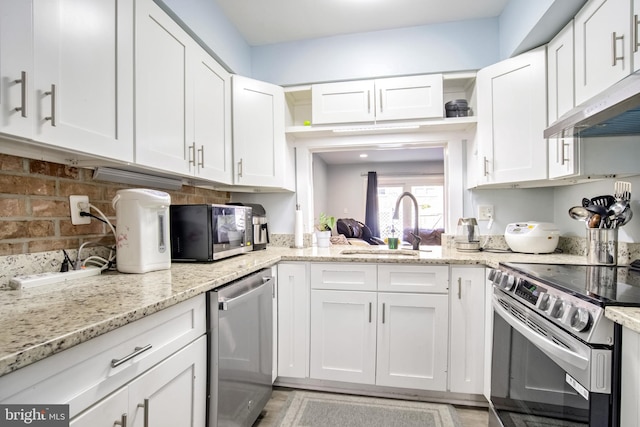 kitchen featuring white cabinetry, sink, stainless steel appliances, and light stone countertops