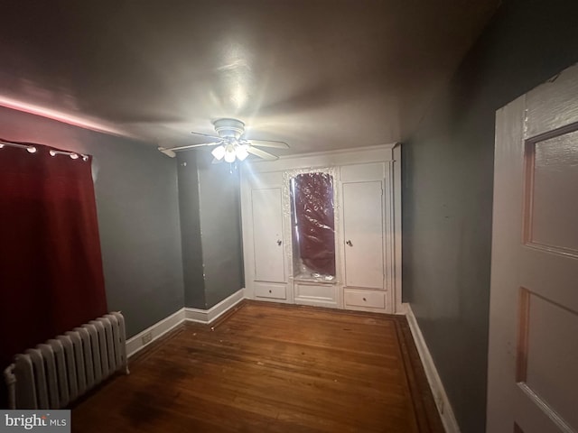 interior space featuring ceiling fan, dark wood-type flooring, and radiator heating unit