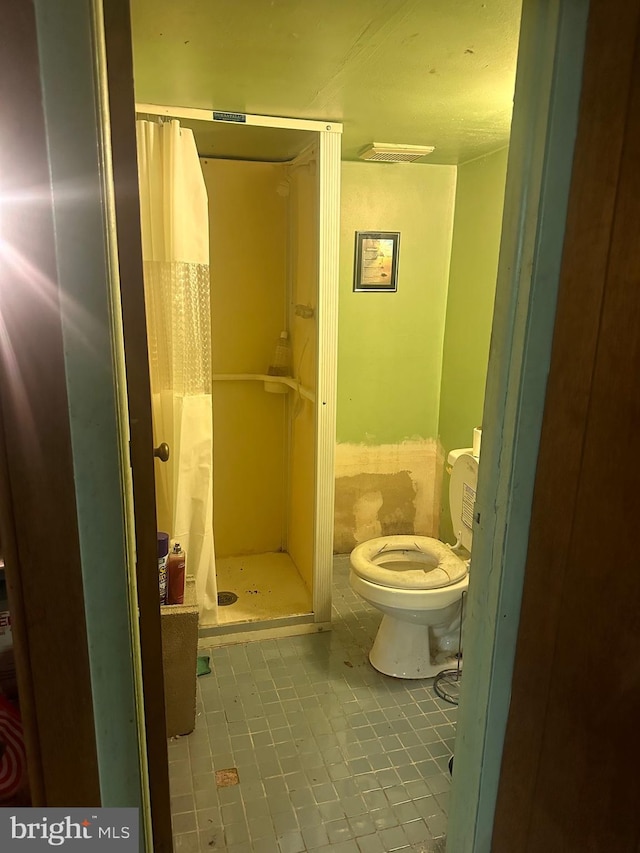 bathroom with curtained shower, toilet, and tile patterned flooring