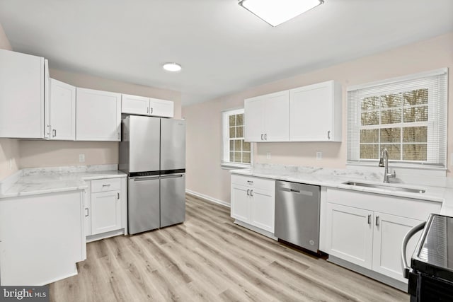 kitchen with appliances with stainless steel finishes, sink, a wealth of natural light, and white cabinets