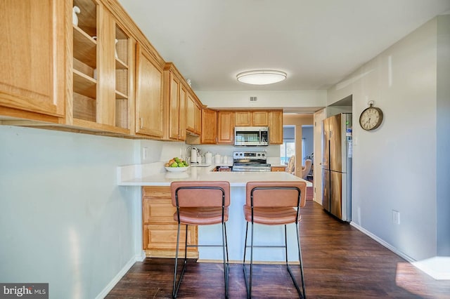 kitchen featuring stainless steel appliances, sink, a kitchen breakfast bar, dark hardwood / wood-style floors, and kitchen peninsula