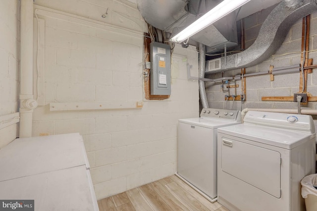 clothes washing area featuring independent washer and dryer, electric panel, and light wood-type flooring