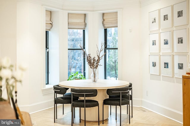 dining room with breakfast area, ornamental molding, and light parquet floors