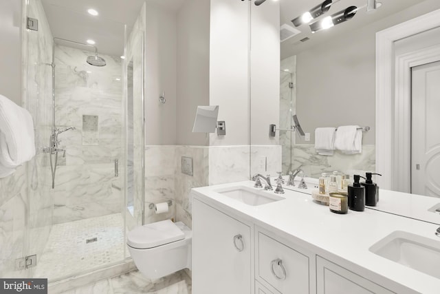 bathroom with vanity, toilet, a shower with shower door, and tile walls