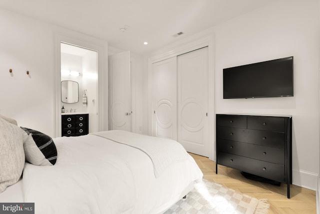 bedroom featuring connected bathroom and light parquet floors