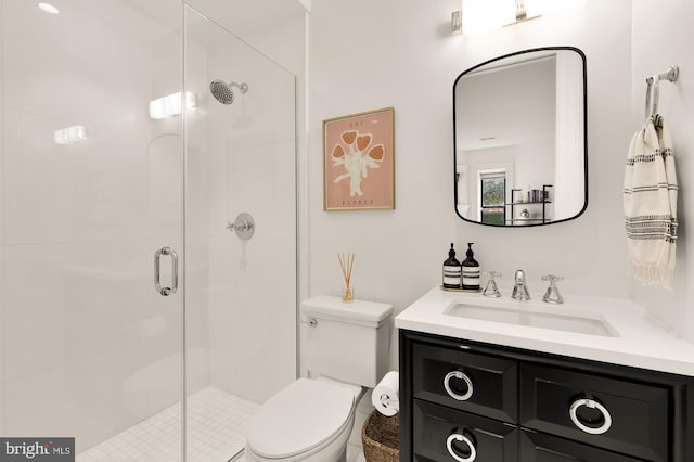 bathroom featuring vanity, a shower with shower door, and toilet