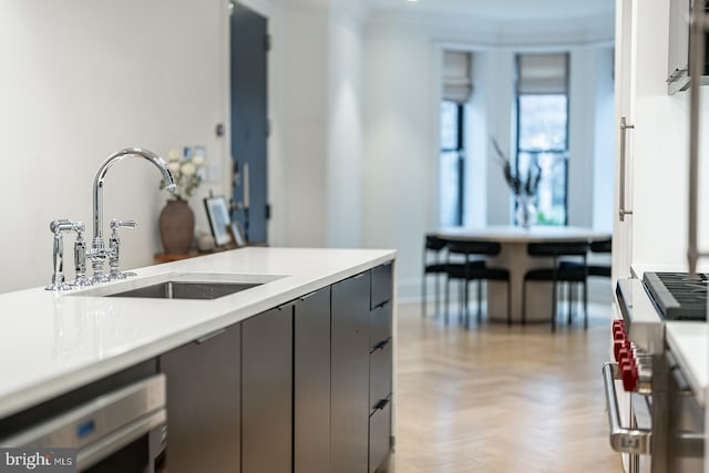 kitchen with gas range, sink, gray cabinetry, dishwashing machine, and light parquet flooring