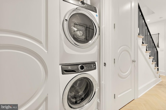 washroom with light parquet floors and stacked washing maching and dryer