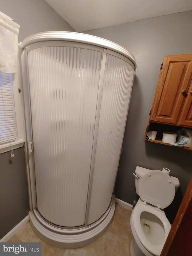 bathroom featuring toilet, a shower with door, and tile patterned flooring