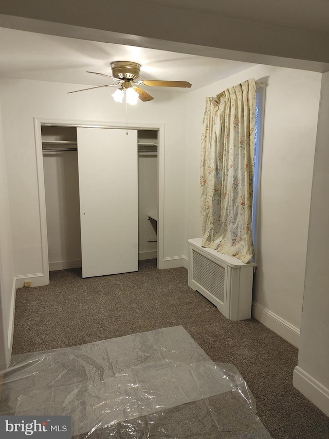 unfurnished bedroom featuring ceiling fan, a closet, and dark carpet