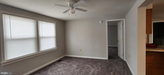 empty room featuring ceiling fan and dark carpet