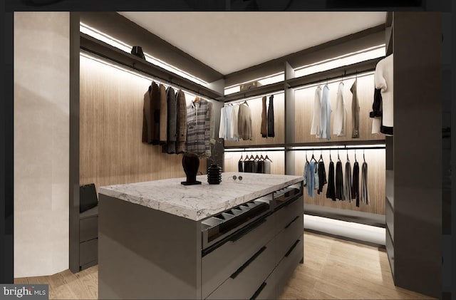 walk in closet with light hardwood / wood-style flooring