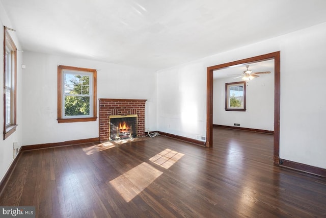 unfurnished living room with a fireplace, plenty of natural light, and dark hardwood / wood-style floors