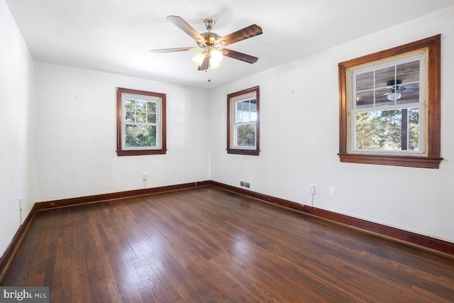 empty room with ceiling fan, dark hardwood / wood-style floors, and a healthy amount of sunlight