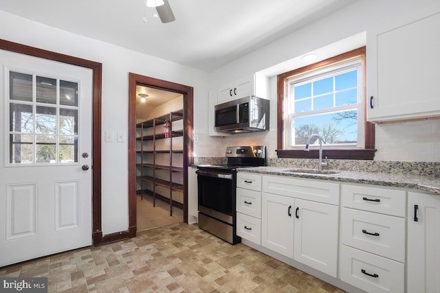 kitchen with white cabinets, light stone countertops, sink, and stainless steel appliances