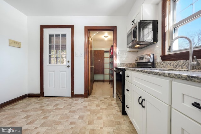 kitchen featuring sink, white cabinetry, a healthy amount of sunlight, appliances with stainless steel finishes, and dark stone counters