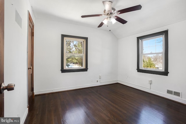 empty room featuring ceiling fan, a wealth of natural light, dark hardwood / wood-style floors, and vaulted ceiling