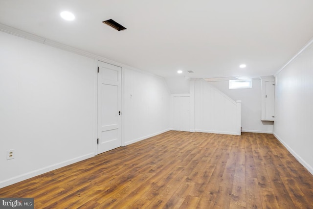 basement with dark wood-type flooring and ornamental molding