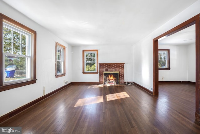 unfurnished living room with dark wood-type flooring and a brick fireplace